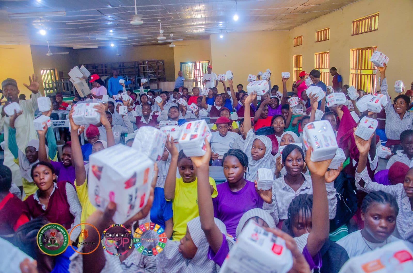 Students raise packs of menstrual products in celebration at the Menstrual Hygiene Day campaign